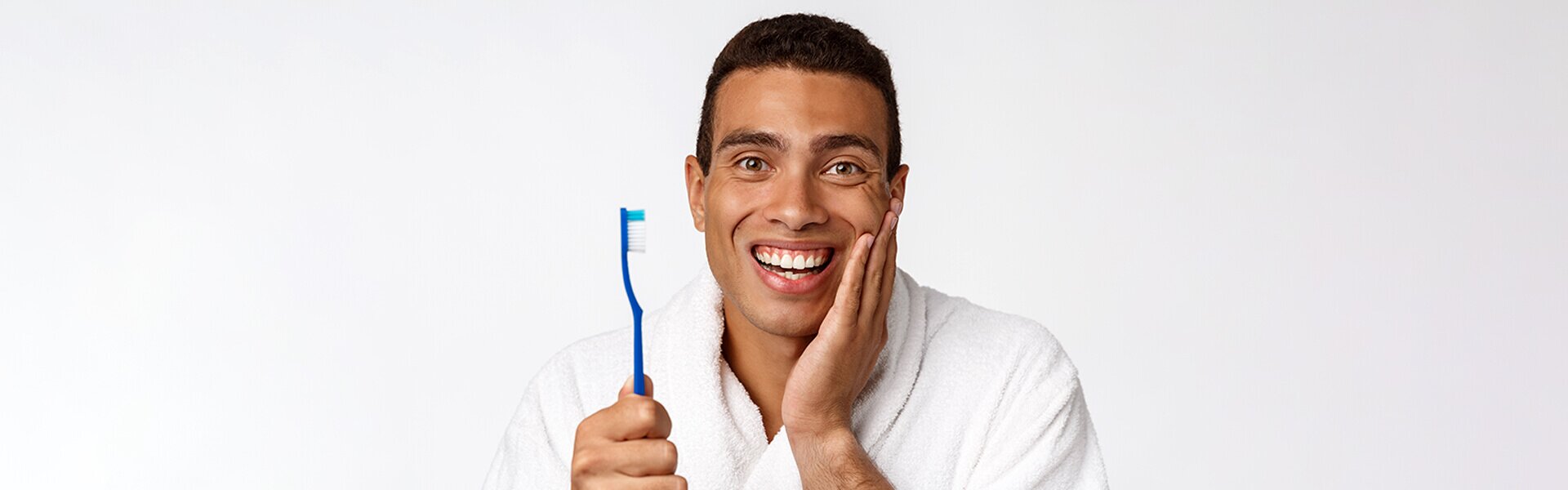 dentist patient model holding a toothbrush up and holding the side of his face