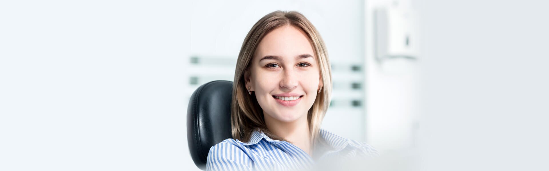 dentist patient model sitting in a dental chair smiling